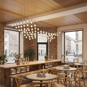 Cluster of small glass pendant lights hanging over a long wooden communal table in a brick-walled Copenhagen restaurant